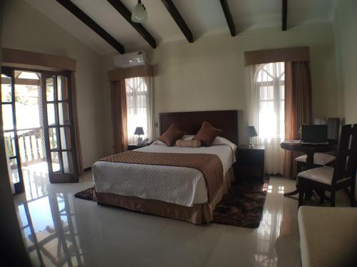 - une chambre avec un grand lit dans une pièce dotée de fenêtres dans l'établissement Hotel Boutique Casamagna, à Cochabamba