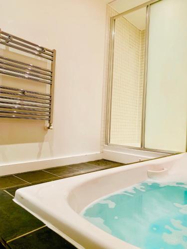 a bathroom with a tub with a mirror and a window at Glasgow City Centre - The PENTHOUSE with RiverViews - (Duplex, 3 Bedrooms, 3 Bathrooms, 2 Living rooms/Kitchen, Private SKY Terrace, 2 Parkings, Top Floor, Huge - 2100 sq ft, SECC HYDRO) in Glasgow