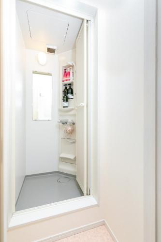 a small white refrigerator with a mirror in a room at Villa de Class in Osaka