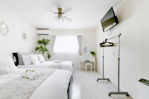 two beds in a white room with a ceiling fan at Villa de Class in Osaka