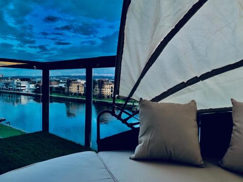 eine Couch auf einem Balkon mit Blick auf einen Fluss in der Unterkunft Glasgow City Centre - The PENTHOUSE with RiverViews - (Duplex, 3 Bedrooms, 3 Bathrooms, 2 Living rooms/Kitchen, Private SKY Terrace, 2 Parkings, Top Floor, Huge - 2100 sq ft, SECC HYDRO) in Glasgow