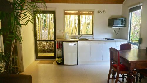 a kitchen with a white refrigerator and a table and a window at Wharepuke Subtropical Accommodation in Kerikeri