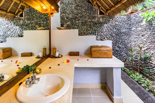 uma casa de banho com um lavatório e uma parede de pedra em Taman Selini Wahana Beach Resort em Pemuteran