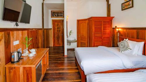 a hotel room with two beds and a television at Mango Kesararam in Siem Reap