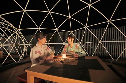 two women sitting at a table with wine glasses at Aburaya Tousen in Yamanouchi