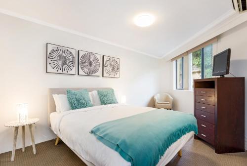 a white bedroom with a large bed and a tv at Inner city retreat in Pyrmont 1 bdrm with Car space - 28 Mill in Sydney