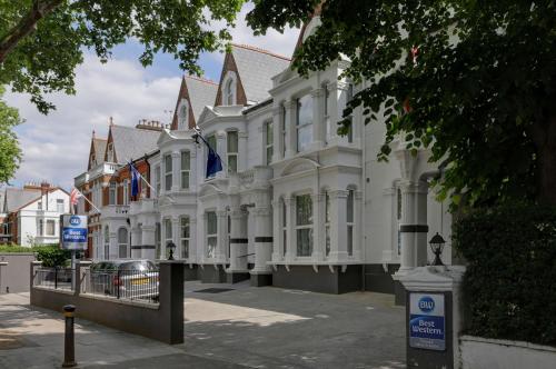 un grand bâtiment blanc avec drapeaux devant lui dans l'établissement Best Western Chiswick Palace & Suites London, à Londres