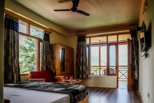 a bedroom with a bed and a large window at Soham's Chateau De Naggar - Manali in Nagar