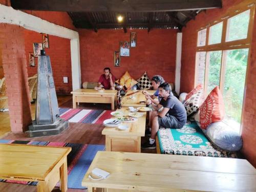 un groupe de personnes assises à des tables dans une pièce dans l'établissement Soham's Chateau De Naggar - Manali, à Nagar