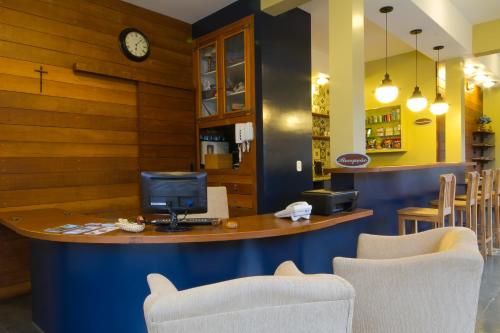 a bar in a restaurant with two chairs and a clock at Pousada Il Villaggio in Santo Antônio do Pinhal