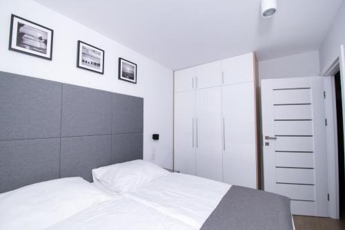 a bedroom with a white bed and white cabinets at Apartament K&K Klifowa Rewal in Rewal