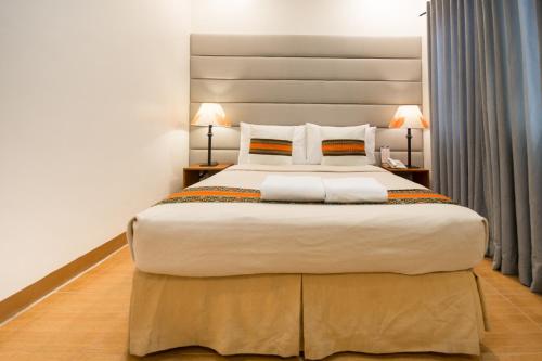 a large bed in a hotel room with two lamps at Sur Beach Resort Boracay in Boracay
