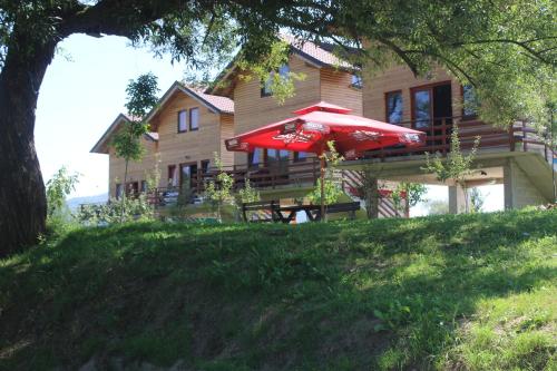 a house with a table and a red umbrella at Holiday homes Piralo in Kostajnica