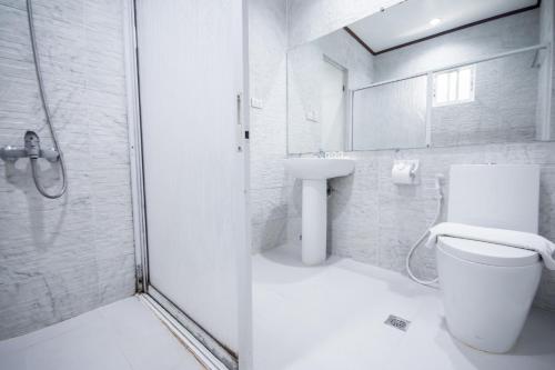a white bathroom with a toilet and a sink at Sur Beach Resort Boracay in Boracay