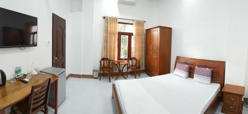 a bedroom with a bed and a desk and a television at Khách Sạn Ngọc Hân in Tinh Bien