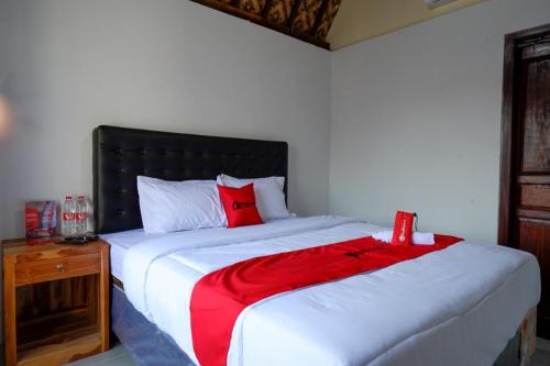 um quarto com uma grande cama branca e um cobertor vermelho em RedDoorz @ Kampoeng Etnik Kebumen 2 em Kebumen
