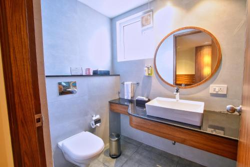 een badkamer met een wastafel, een spiegel en een toilet bij Lilac Hotel, 5th Block in Bangalore