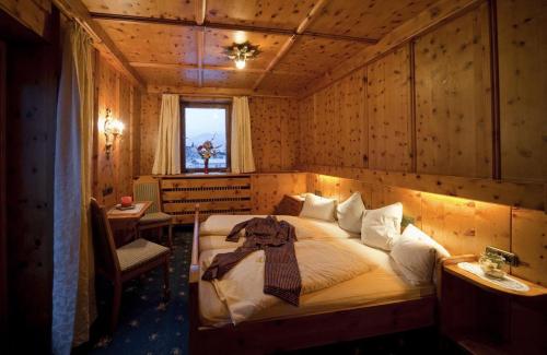 una camera con un letto in una stanza con pareti in legno di Hotel Metzgerwirt a Fieberbrunn
