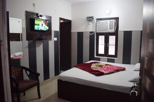a bedroom with a bed and a chair and a television at Hotel Thakur Ji in Haridwār