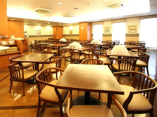 una sala da pranzo vuota con tavoli e sedie di Hotel Route-Inn Nahatomariko a Naha