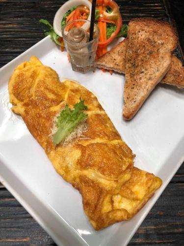 a plate of food with a omelet and bread at Soi One Boutique Bedrooms in Pai
