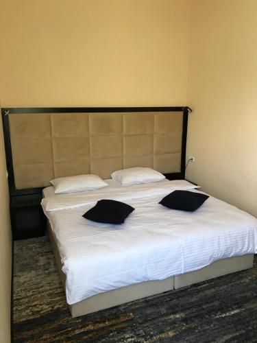 a bedroom with a large bed with black pillows on it at Vanadzor Armenia Hotel in Vanadzor