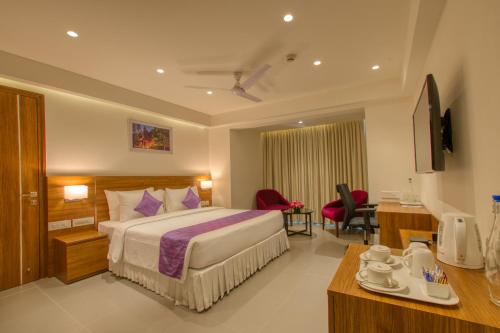 een hotelkamer met een groot bed en een bureau bij Lilac Hotel, 5th Block in Bangalore