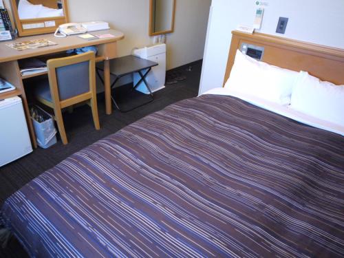 a hotel room with a bed and a desk at Hotel Route-Inn Niigata Kencho-minami in Niigata