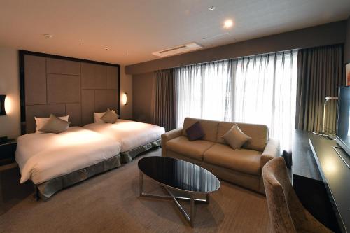 a hotel room with a bed and a couch at Hotel Trusty Nagoya Shirakawa in Nagoya