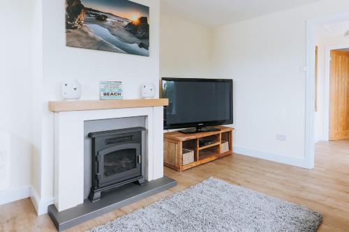 a living room with a fireplace and a tv at Sunset in Newquay