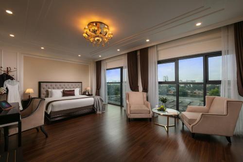 a bedroom with a bed and two chairs and a chandelier at Adonis Hotel in Hanoi