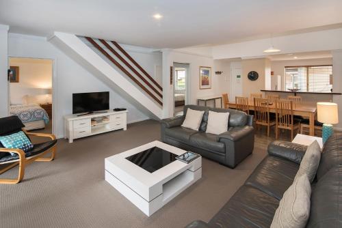 a living room with a couch and a tv and a table at Bayshore Beachside Resort in Dunsborough