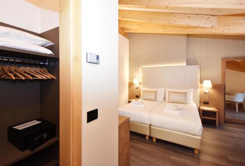 a bedroom with a white bed and a room at X Alp Hotel in Pozza di Fassa