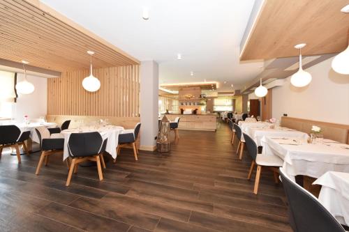 a dining room with white tables and chairs at X Alp Hotel in Pozza di Fassa
