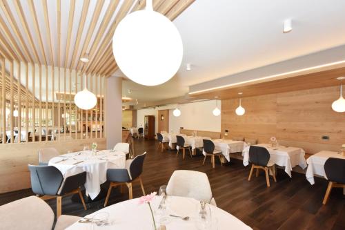 a dining room with white tables and chairs at X Alp Hotel in Pozza di Fassa