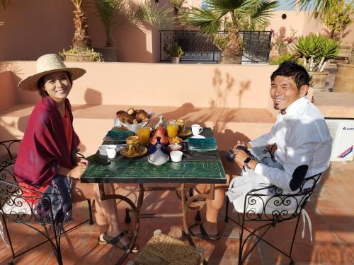 a man and woman sitting at a table with food at Riad Les Nuits de Marrakech in Marrakech