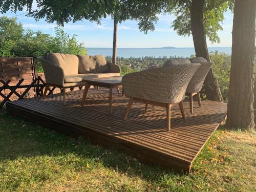 a couch sitting on a wooden deck with chairs at Hillside Apartments in Révfülöp