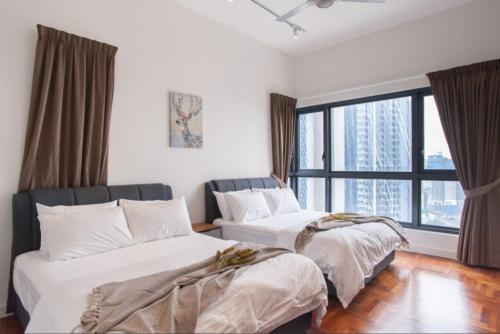 two beds in a room with a large window at KLCC The Mews Home in Kuala Lumpur