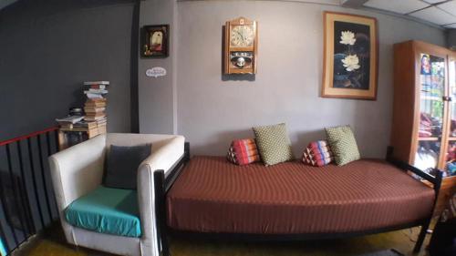 un letto in una stanza con una sedia e un orologio di Muster Guesthouse a Phra Nakhon Si Ayutthaya