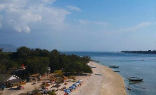 a beach with umbrellas and people on the sand at Sunset Beach Bungalow in Gili Meno