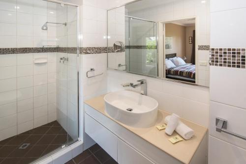 a bathroom with a sink and a shower and a mirror at Bayshore Beachside Resort in Dunsborough