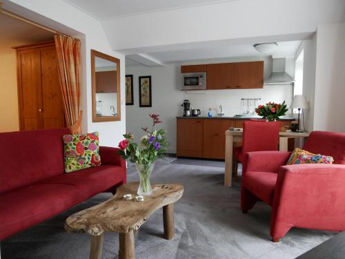 a living room with a red couch and a table at Appartementen de Strandloper in Bergen aan Zee