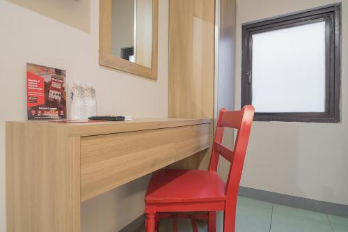 a red chair sitting next to a wooden desk with a window at RedDoorz @ Kiaracondong in Bandung