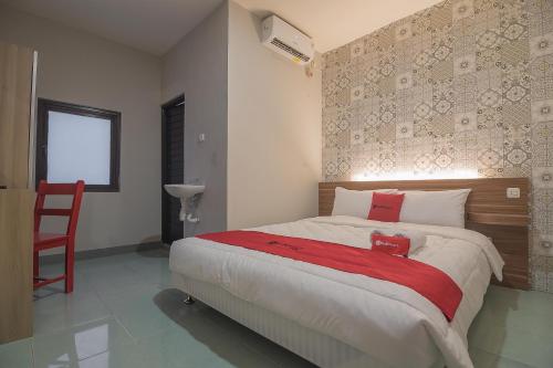 um quarto com uma cama grande e um cobertor vermelho em RedDoorz @ Kiaracondong em Bandung