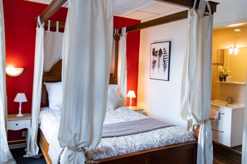 シュリー・シュル・ロワールにあるホテル アンリ IVの赤い壁のベッドルーム1室(天蓋付きベッド1台付)