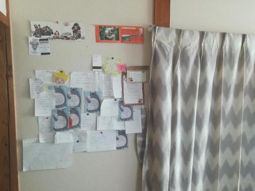 a refrigerator with papers and magnets on a wall at Credo Sasebo in Sasebo