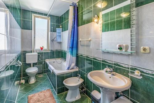 zieloną wyłożoną kafelkami łazienkę z 2 toaletami i umywalką w obiekcie All Seasons Apartment w Puli