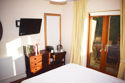 a bedroom with a bed and a dresser with a television at Wings in Oakham