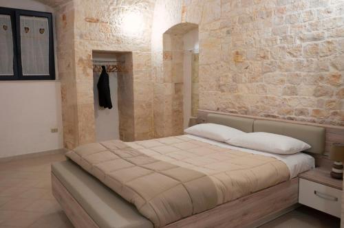a bedroom with a large bed with a stone wall at Pietranuova in Turi