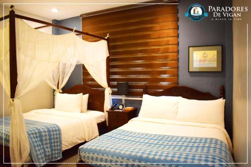 a bedroom with two beds and a wooden headboard at Paradores de Vigan in Vigan